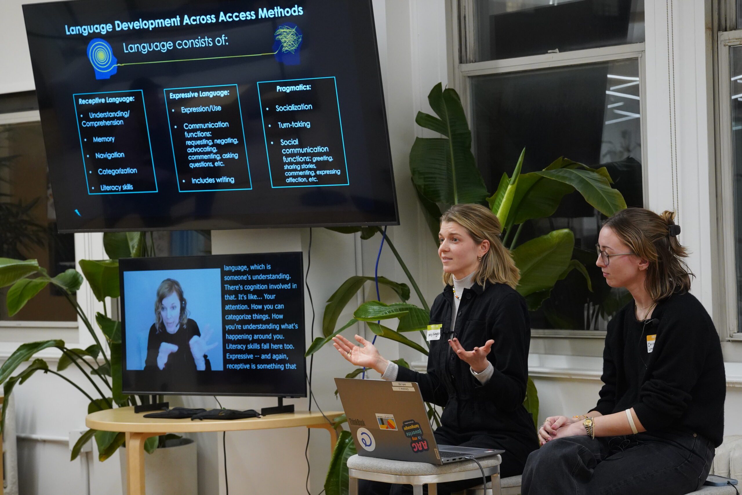 A TV screen with an ASL interpreter and caption on a table next to presenters Molly Ziegler and Christina Lompado.